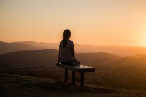 woman sitting on bench over viewing mountain